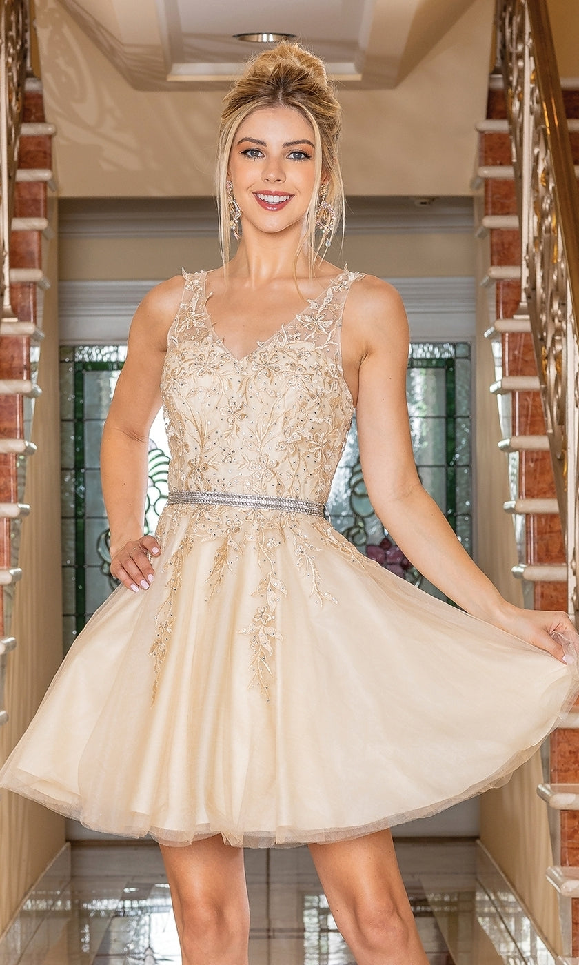 A woman poses indoors on a tiled floor between two staircases, dressed in the Short Prom Dress with Embroidered Sheer Bodice—a sleeveless, knee-length beige A-line party dress featuring delicate embroidery and a jeweled belt.